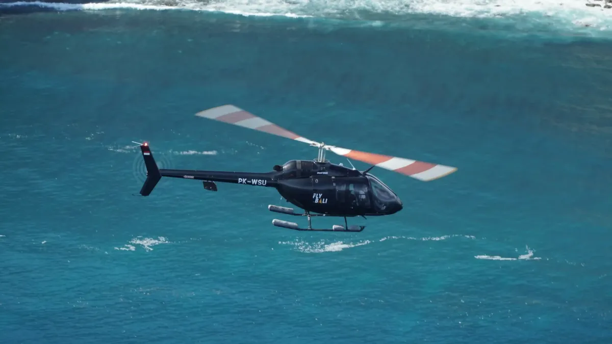 Private helicopter flying low over the sea off Bali