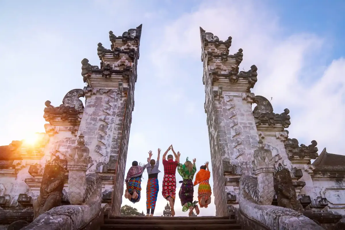 Five travellers in sarongs jumping at the Lempuyang temple gate, East Bali